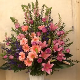 Pink and purple mixed flower arrangement in a white vase