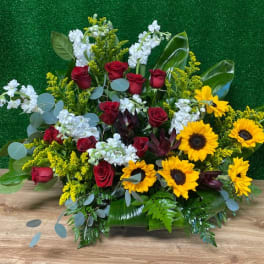 Red roses and yellow sunflowers in a low floral arrangement