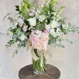 Tall bouquet of white and pale pink flowers in a glass vase