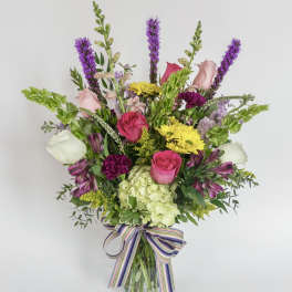 Mixed bouquet in a glass vase with pink, white, yellow, and purple flowers