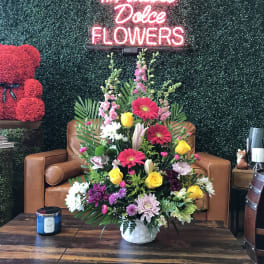 Mixed flower arrangement in a white basket on a table