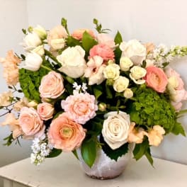 Large pastel bouquet of roses and ranunculus in a silver vase