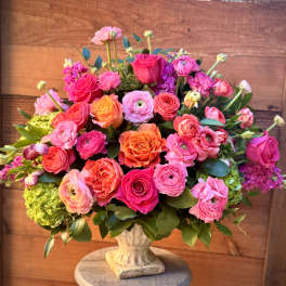 Mixed pink and orange flower arrangement in a stone vase