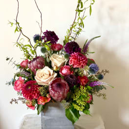 Tall mixed flower arrangement in a square silver vase