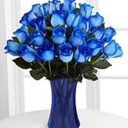 Blue roses arranged in a tall blue vase