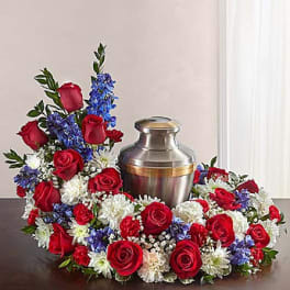 Red roses and white-blue flowers arranged around a metal urn