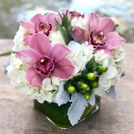 Pink orchids and white hydrangeas in a green glass vase