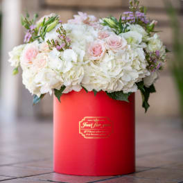 White and blush flowers arranged in a red hat box