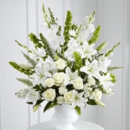 White lilies and roses arranged in a white vase