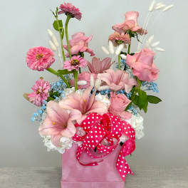 Pink floral arrangement in a pink box with a polka-dot ribbon