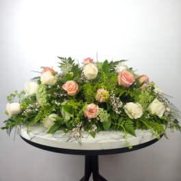 Low floral arrangement of white and peach roses on a round table