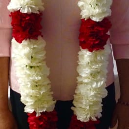 Person wearing long white and red flower garlands around the neck
