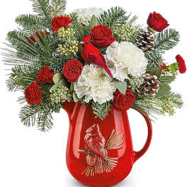 Red and white floral arrangement in a red pitcher vase
