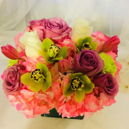 Pink and purple rose bouquet with green orchids in a black container