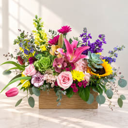 Colorful mixed flower arrangement in a wooden box with a sunflower and pink lily