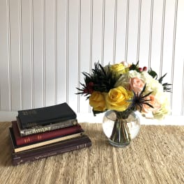 Bouquet of yellow, white, and peach roses in a glass vase