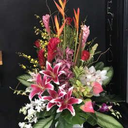 Tall tropical floral arrangement with pink lilies and orchids in a vase