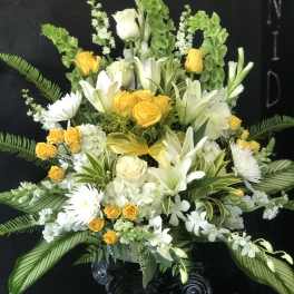 White and yellow floral arrangement in a black pedestal vase