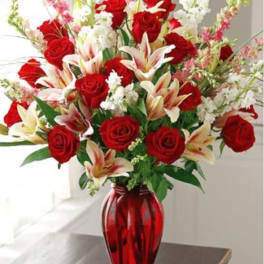 Red roses and white lilies in a red glass vase