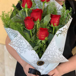 Bouquet of red roses wrapped in white paper with a black ribbon