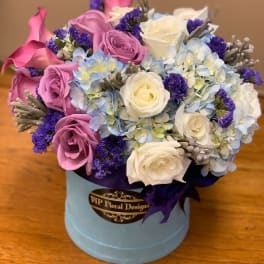 Bouquet of pink and white roses with blue hydrangeas in a round box