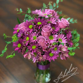 Pink and purple bouquet of roses and daisies in a glass vase