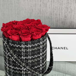 Red roses arranged in a black tweed-style round box with a handle