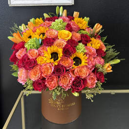 Large bouquet of roses, sunflowers, and lilies in a brown box