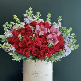 Red roses and pink orchids in a white hat box