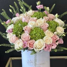 Pink and white roses with green hydrangeas in a white hatbox