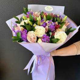 Bouquet of cream, blush, and purple flowers wrapped in lavender paper
