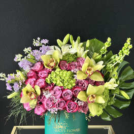 Pink roses and yellow orchids in a teal hatbox