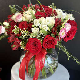 Bouquet of red and white roses in a glass vase with a red ribbon