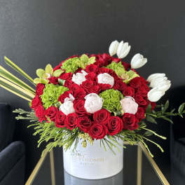 Red roses, white tulips, and green hydrangeas in a white hat box