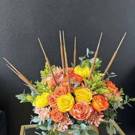 Orange and yellow floral arrangement in a pumpkin-shaped container