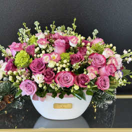 Pink and lavender rose arrangement in a white container