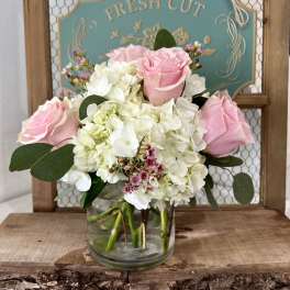 Pink roses and white hydrangeas in a clear glass vase