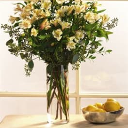 Tall bouquet of pale yellow flowers in a clear glass vase