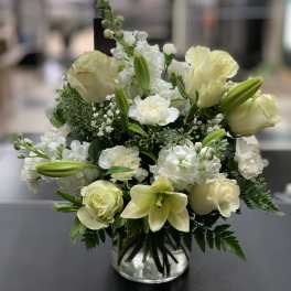 White and pale yellow floral arrangement in a clear glass vase