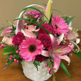 Pink and white mixed flower arrangement in a white basket