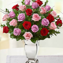 Bouquet of red, pink, and lavender roses in a clear glass vase