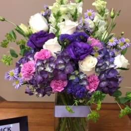 Purple, white, and pink bouquet in a clear glass vase