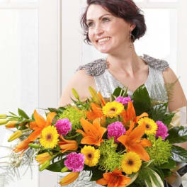 Woman holding a large bouquet of orange lilies, yellow daisies, and pink carnations