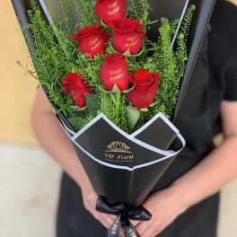 Bouquet of red roses wrapped in black paper with a birthday message