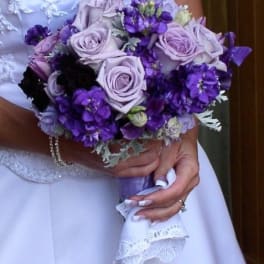 Bride holding a bouquet of lavender roses and purple flowers