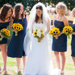 Bride and bridesmaids holding sunflower bouquets outdoors