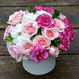 Pink roses and magenta carnations in a white vase