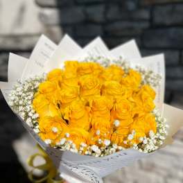 Bouquet of yellow roses with white baby's breath in white paper wrap