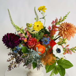 Colorful mixed flower arrangement in a white pedestal vase