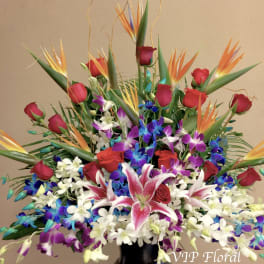 Large tropical bouquet with red roses, orchids, and bird of paradise in a black vase
